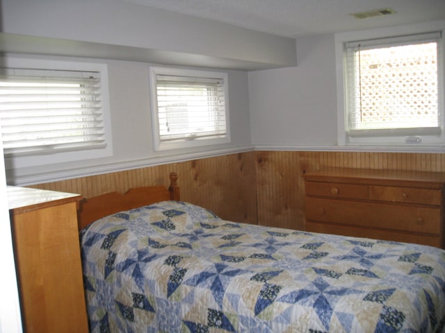 bedroom featuring wainscoting, visible vents, and multiple windows