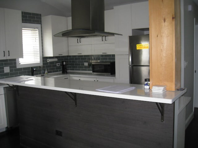 kitchen with freestanding refrigerator, a kitchen breakfast bar, ventilation hood, backsplash, and oven