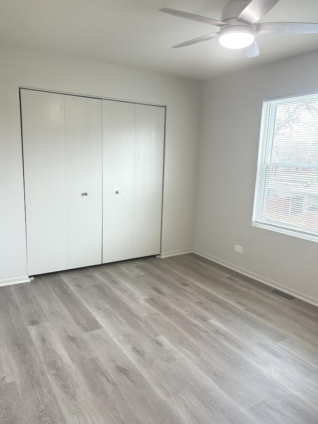unfurnished bedroom featuring a closet, baseboards, visible vents, and light wood-style floors