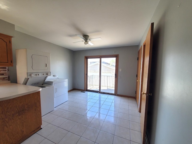 washroom with baseboards, ceiling fan, light tile patterned floors, and stacked washer / dryer
