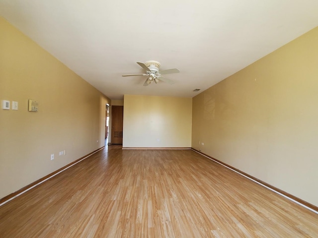 empty room featuring light wood-style floors, baseboards, a ceiling fan, and visible vents