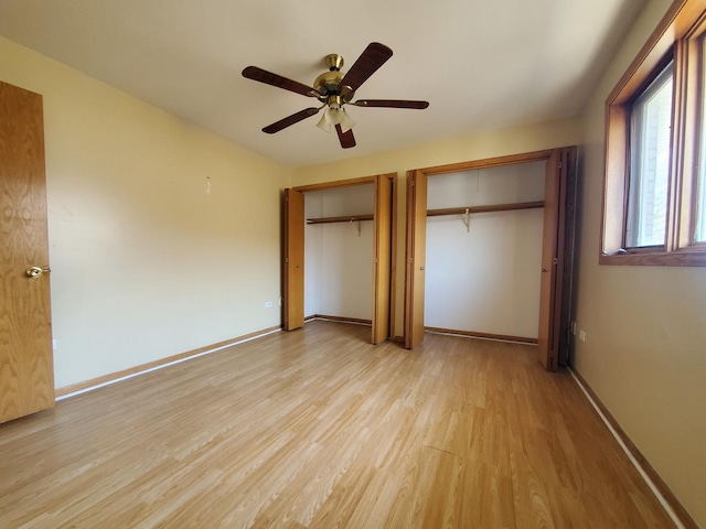 unfurnished bedroom featuring multiple closets, ceiling fan, baseboards, and light wood-style flooring