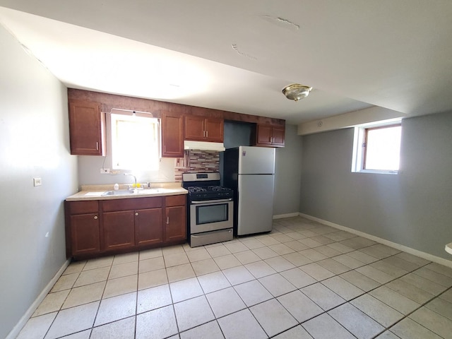 kitchen with a sink, stainless steel gas range, freestanding refrigerator, and a wealth of natural light