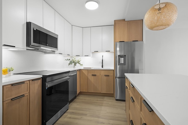 6301 N Sheridan Rd Unit 12C, Chicago, IL 60660 - kitchen featuring appliances with stainless steel finishes, a sink, light wood finished floors, light countertops, and white cabinets
