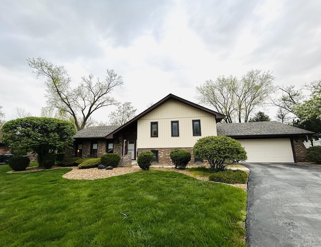 tri-level home with a front lawn, brick siding, a garage, and aphalt driveway