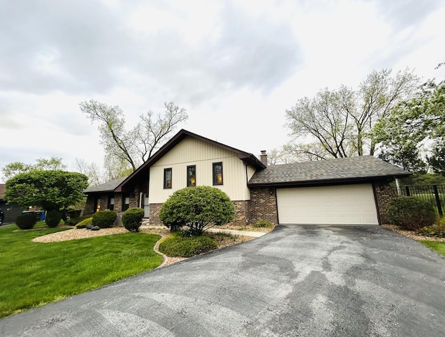 view of front of property featuring aphalt driveway, fence, brick siding, a garage, and a front lawn