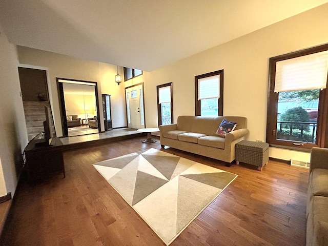 living area with a wealth of natural light, visible vents, wood finished floors, and baseboards