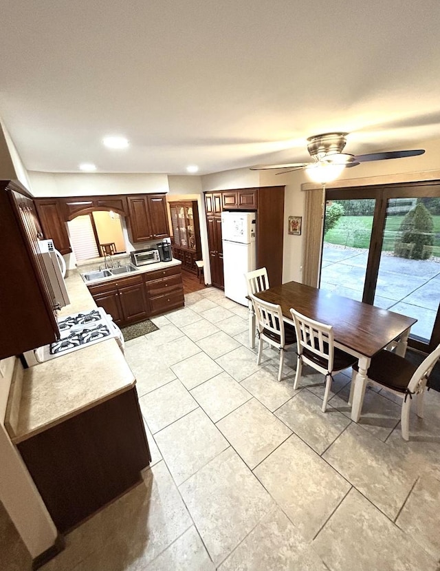 kitchen with a sink, white appliances, light countertops, a ceiling fan, and light tile patterned floors