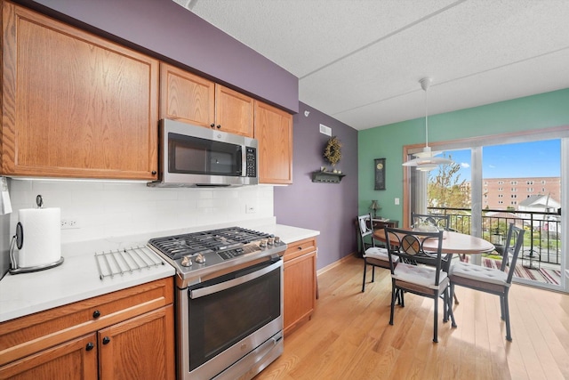 kitchen featuring light countertops, light wood-style flooring, appliances with stainless steel finishes, and tasteful backsplash