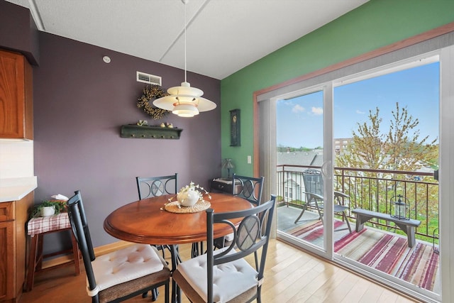 dining area with light wood-style floors and visible vents
