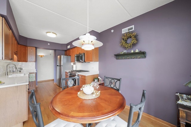 dining space with light wood-type flooring, baseboards, and visible vents