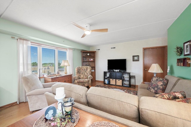 living area featuring visible vents, baseboards, ceiling fan, and wood finished floors