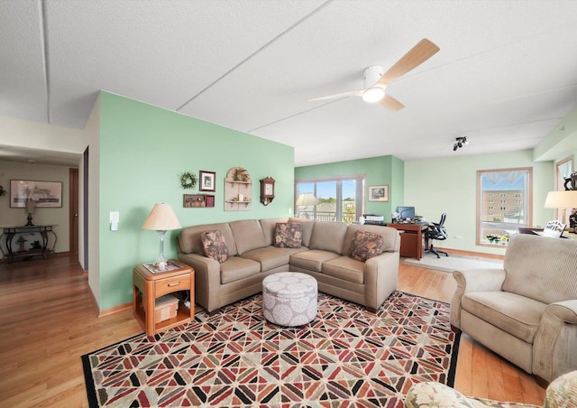 living room featuring baseboards, ceiling fan, and wood finished floors
