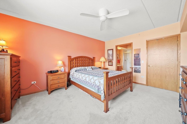 bedroom featuring a ceiling fan, baseboards, light carpet, and ensuite bathroom