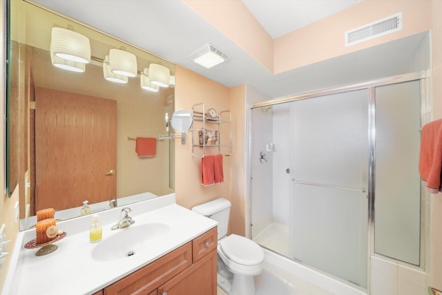 bathroom featuring toilet, visible vents, a shower stall, and vanity