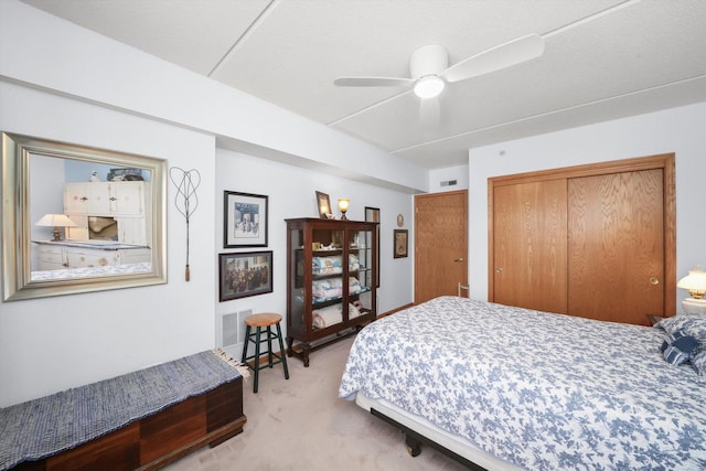 carpeted bedroom with ceiling fan, visible vents, and a closet