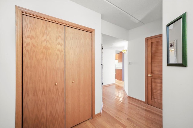hall with baseboards and light wood-style flooring