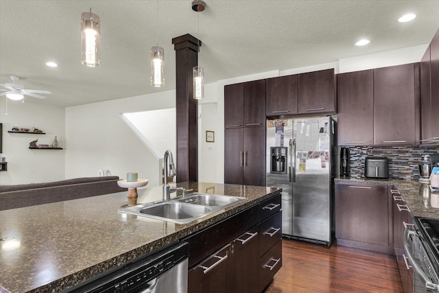 kitchen featuring appliances with stainless steel finishes, a sink, a ceiling fan, dark wood-type flooring, and tasteful backsplash