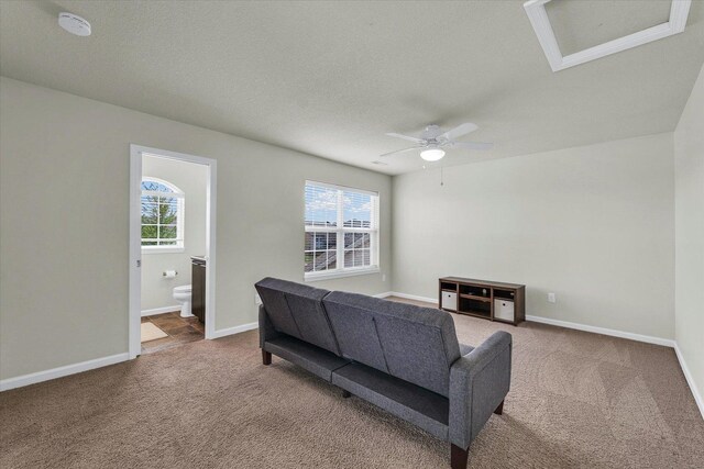 carpeted living room with ceiling fan, baseboards, and a textured ceiling