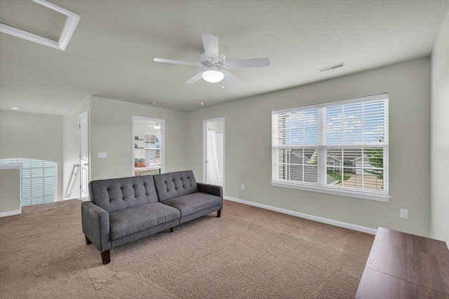 carpeted living area with baseboards, ceiling fan, and a textured ceiling
