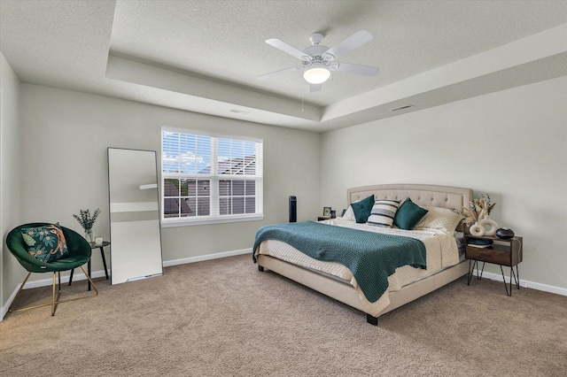 carpeted bedroom with a textured ceiling, baseboards, a raised ceiling, and ceiling fan