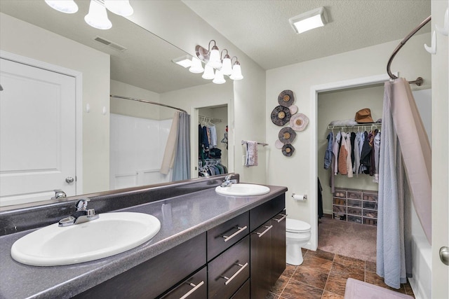 bathroom featuring toilet, a spacious closet, double vanity, a shower with curtain, and a textured ceiling
