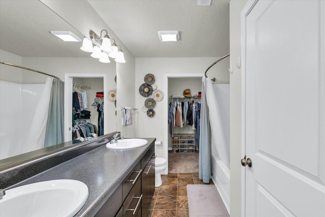 bathroom featuring a walk in closet, toilet, curtained shower, double vanity, and a textured ceiling