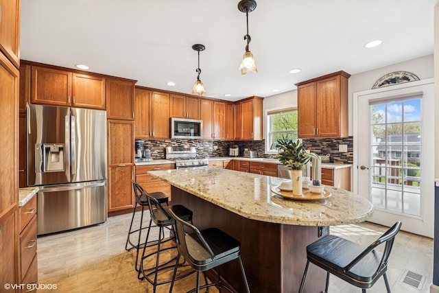 701 N Coolidge Ave, Palatine, IL 60067 - kitchen featuring stainless steel appliances, a breakfast bar area, brown cabinets, backsplash, and light stone countertops