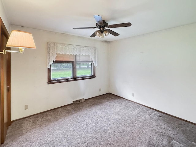 carpeted spare room featuring visible vents, baseboards, and ceiling fan