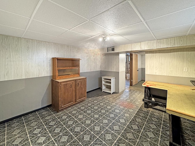 kitchen with wooden walls, a drop ceiling, and visible vents