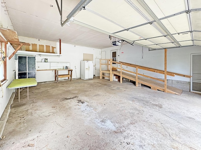 garage featuring a garage door opener and white refrigerator with ice dispenser