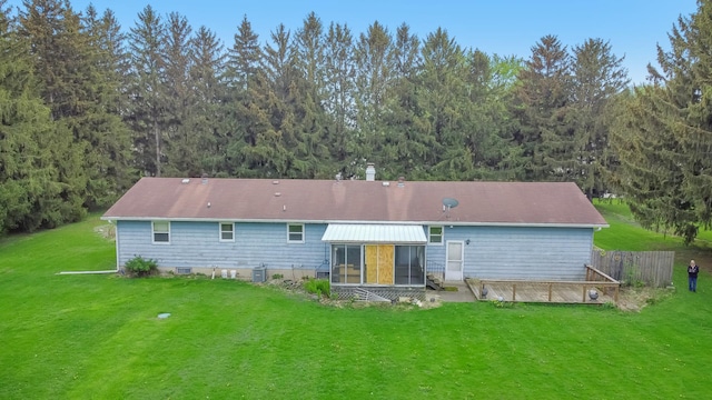 rear view of house featuring a sunroom, a yard, and a forest view