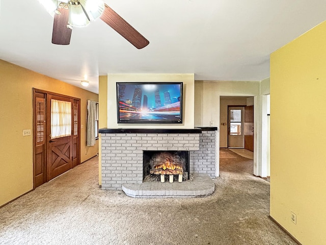 living area with carpet, a brick fireplace, and ceiling fan