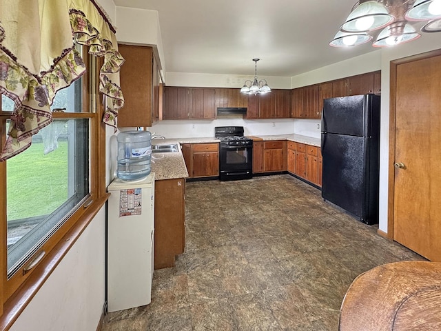 kitchen with a notable chandelier, a sink, light countertops, under cabinet range hood, and black appliances