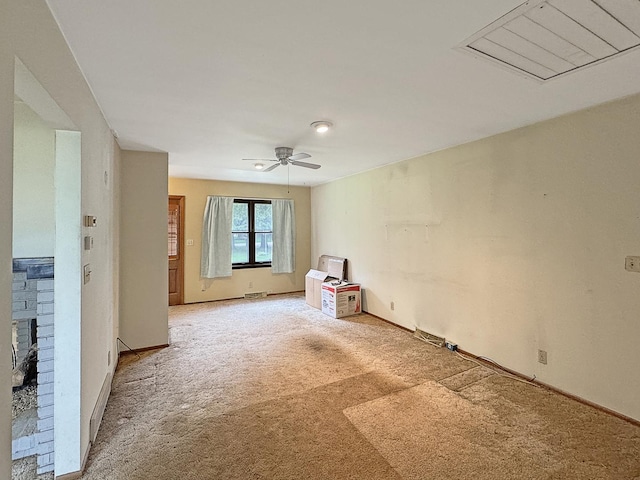 empty room with baseboards, light carpet, a ceiling fan, and a brick fireplace