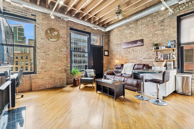 living area with rail lighting, brick wall, and wood finished floors