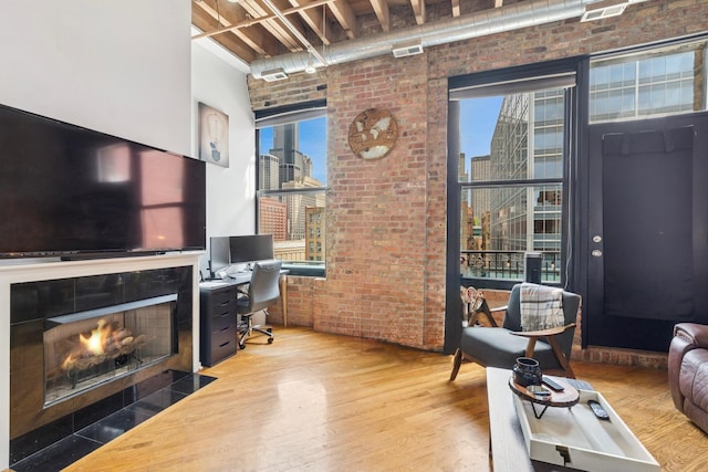 office area with beam ceiling, wood finished floors, and brick wall