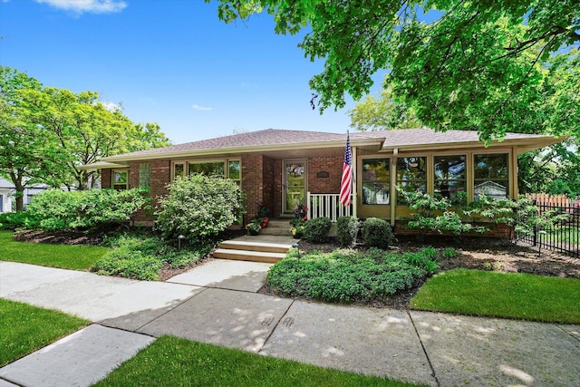 ranch-style home featuring fence and brick siding