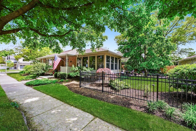 ranch-style home featuring fence, a sunroom, and brick siding