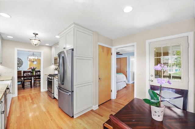kitchen with appliances with stainless steel finishes, light wood-type flooring, white cabinets, light stone counters, and recessed lighting