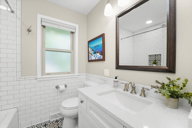 bathroom featuring toilet, tile walls, a shower, vanity, and a wainscoted wall