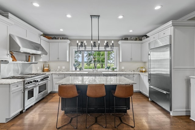 kitchen featuring white cabinets, high quality appliances, a center island, and wall chimney exhaust hood