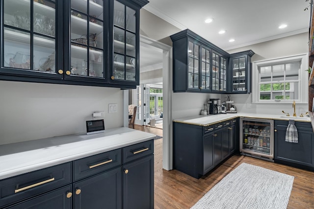 bar featuring wine cooler, wet bar, dark wood-type flooring, recessed lighting, and crown molding