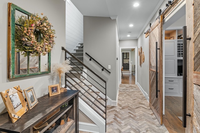 hallway with recessed lighting, a barn door, baseboards, ornamental molding, and stairway
