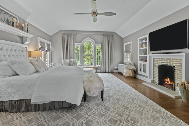 bedroom with vaulted ceiling, dark wood-style flooring, a fireplace, a ceiling fan, and baseboards