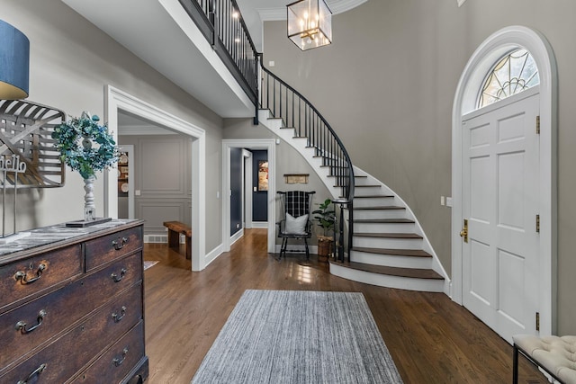 entrance foyer featuring a towering ceiling, stairway, wood finished floors, and baseboards