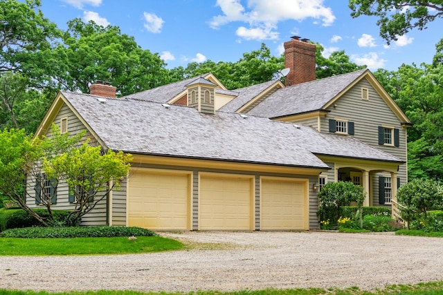 view of front facade with a chimney, driveway, and an attached garage