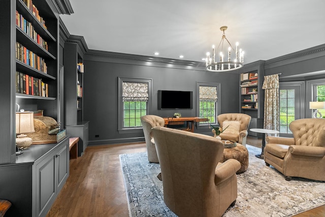 living room featuring a notable chandelier, crown molding, plenty of natural light, and wood finished floors