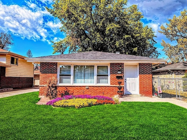 view of front of home with brick siding, fence, and a front yard