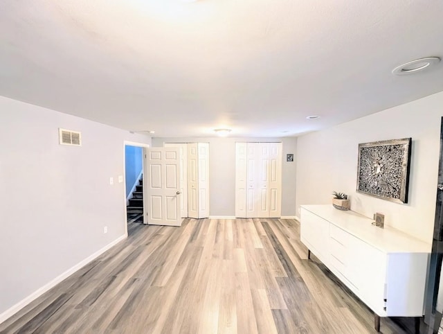 interior space with stairway, visible vents, baseboards, and light wood finished floors